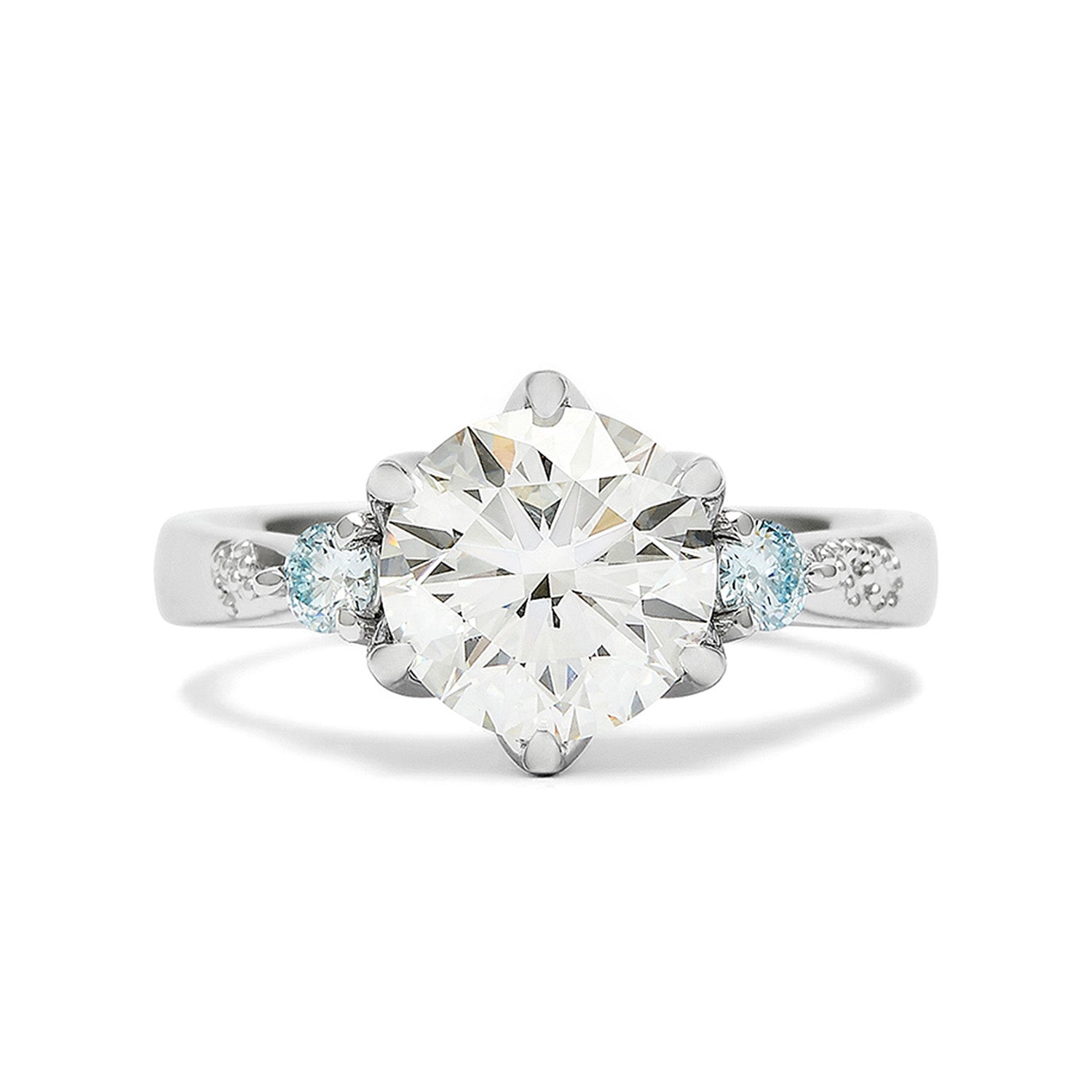 Faith Jewels Lotus engagement ring featuring a round brilliant-cut diamond flanked by two pear-cut aquamarines on a tapered band, inspired by the lotus flower