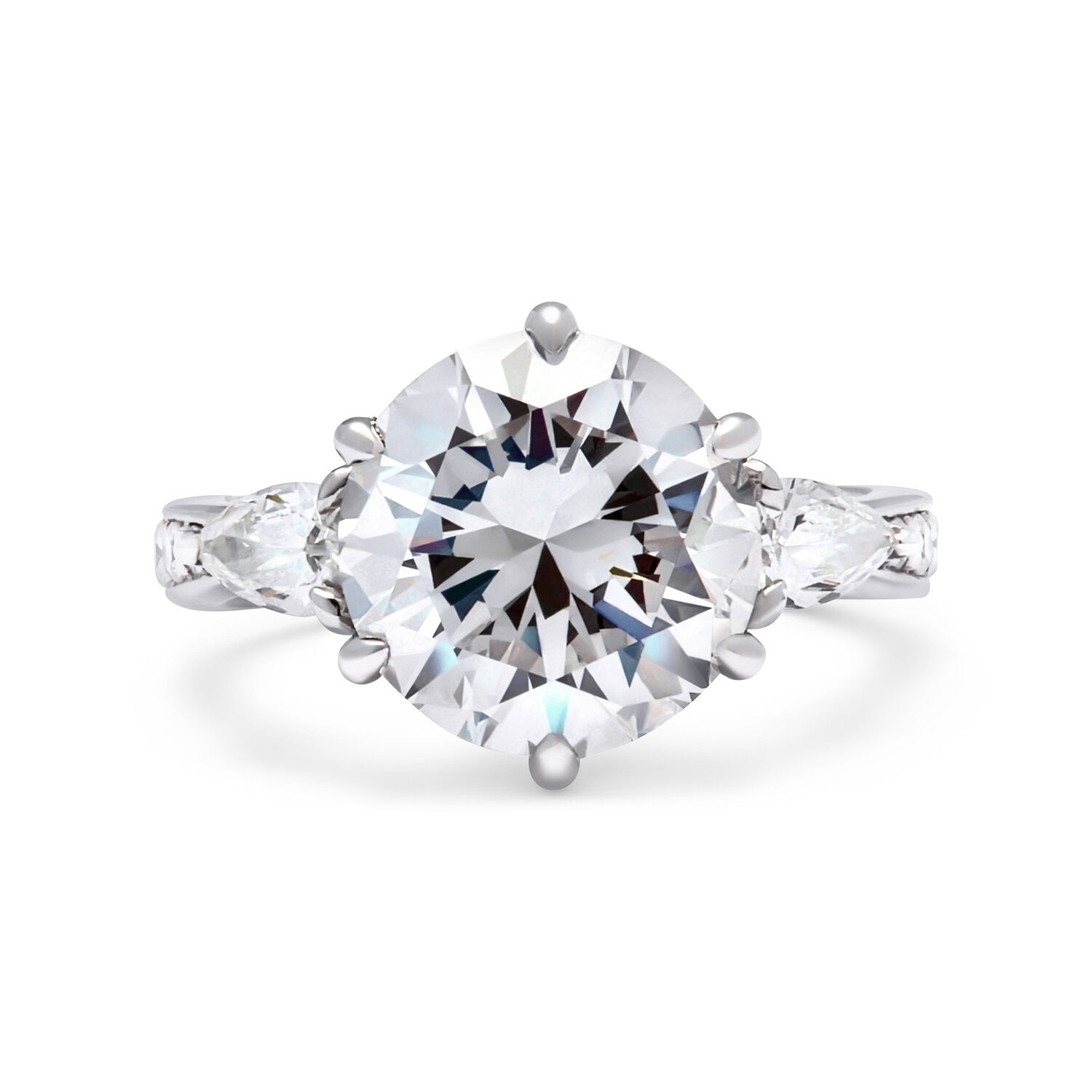 Faith Jewels Lotus engagement ring featuring a round brilliant-cut diamond flanked by two pear-cut diamonds on a tapered pavé diamond band, inspired by the lotus flower