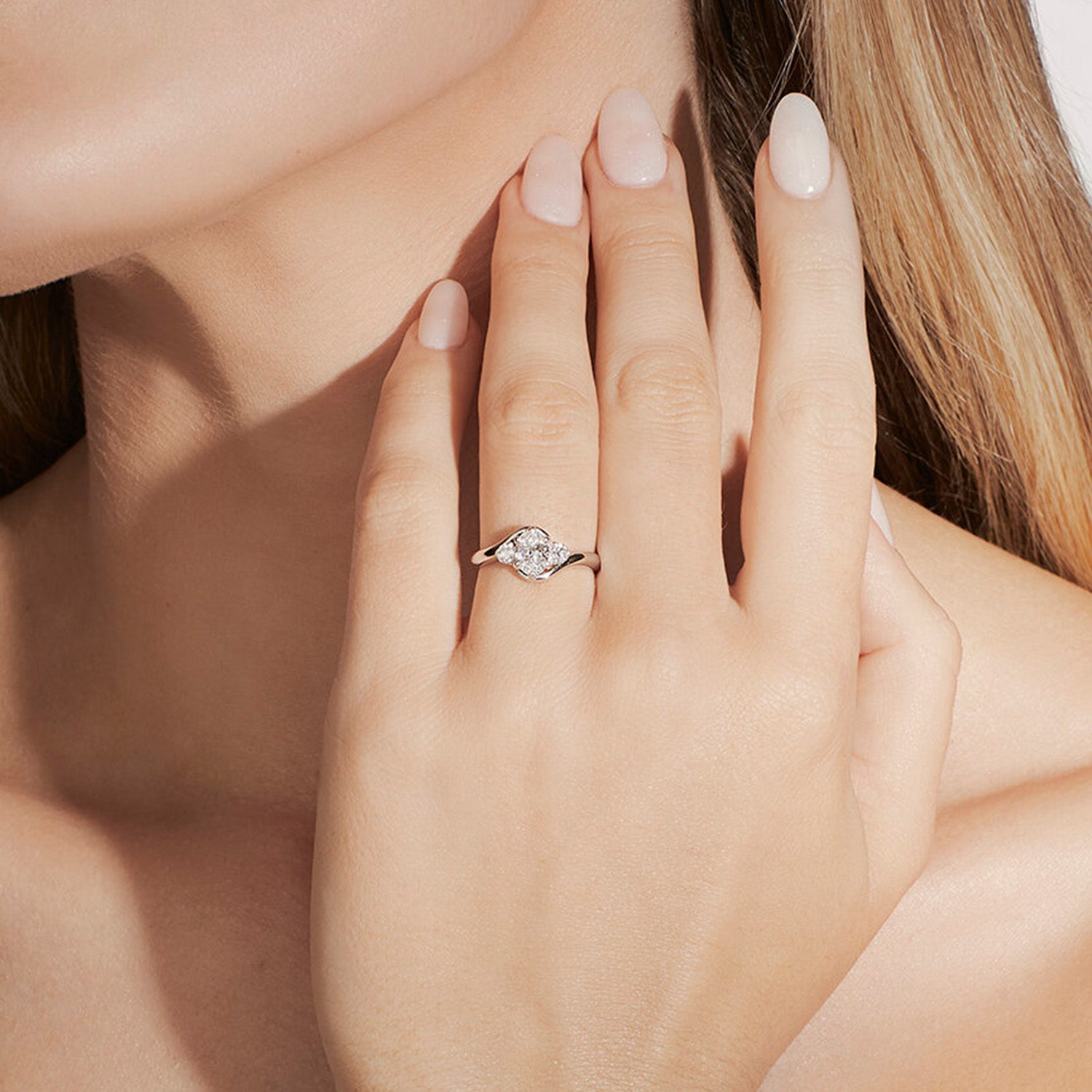 Faith Jewels Rue diamond engagement ring with a round brilliant-cut center diamond, flanked by two smaller brilliant-cut diamonds, featuring a twist band design