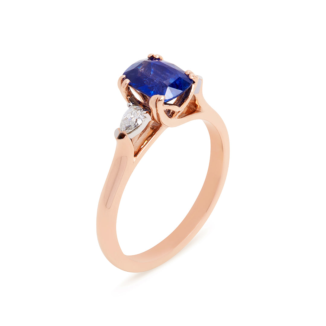 Sheree trilogy engagement ring featuring a royal blue oval-cut sapphire flanked by pear-cut white diamonds in rose gold band