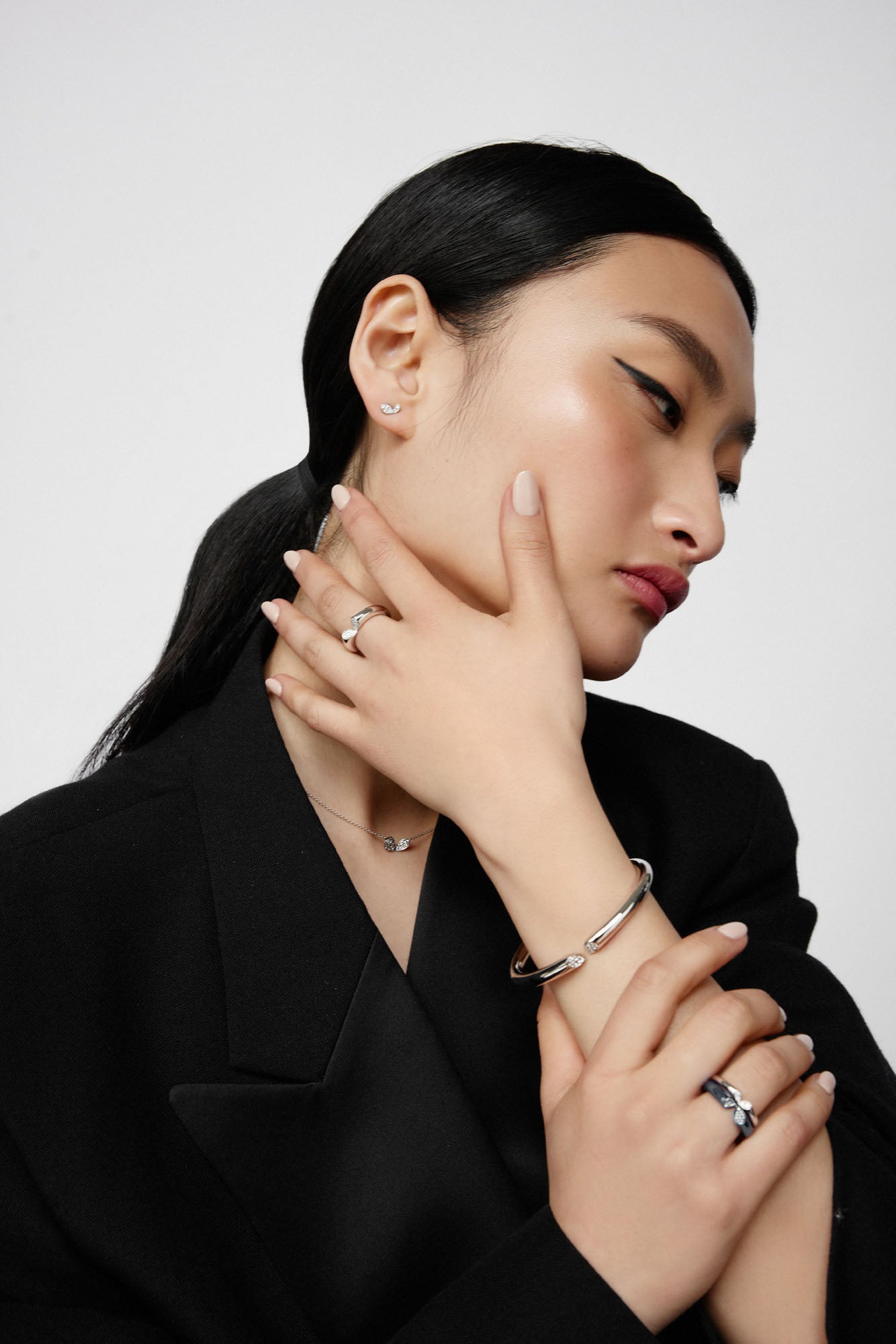 Platinum diamond bangle with heart-shaped lily motif and pavé-set diamonds from Whispers of Love, worn on model with collection pieces.