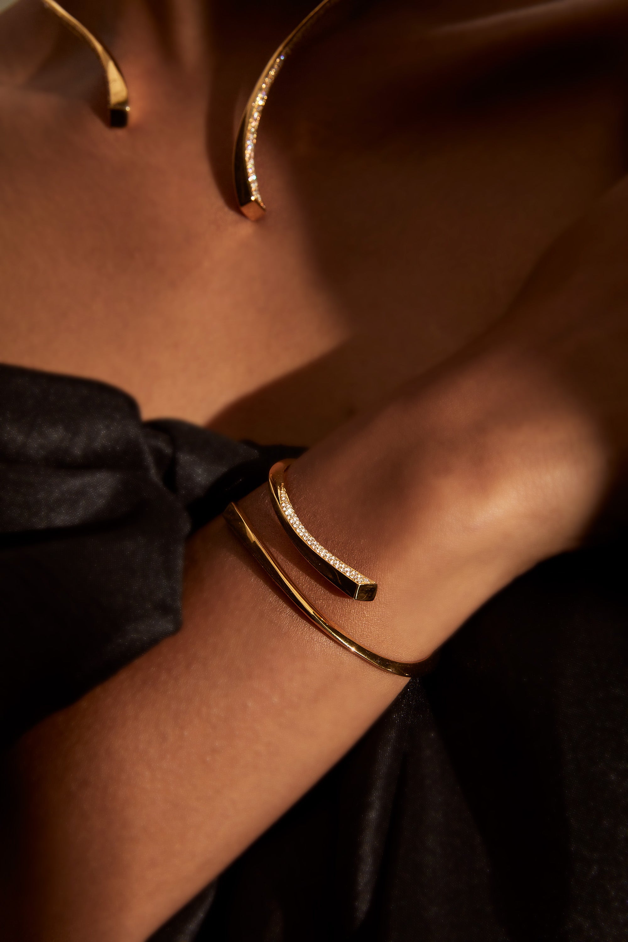Yellow gold bangle and necklace in twist design with pave diamonds on model