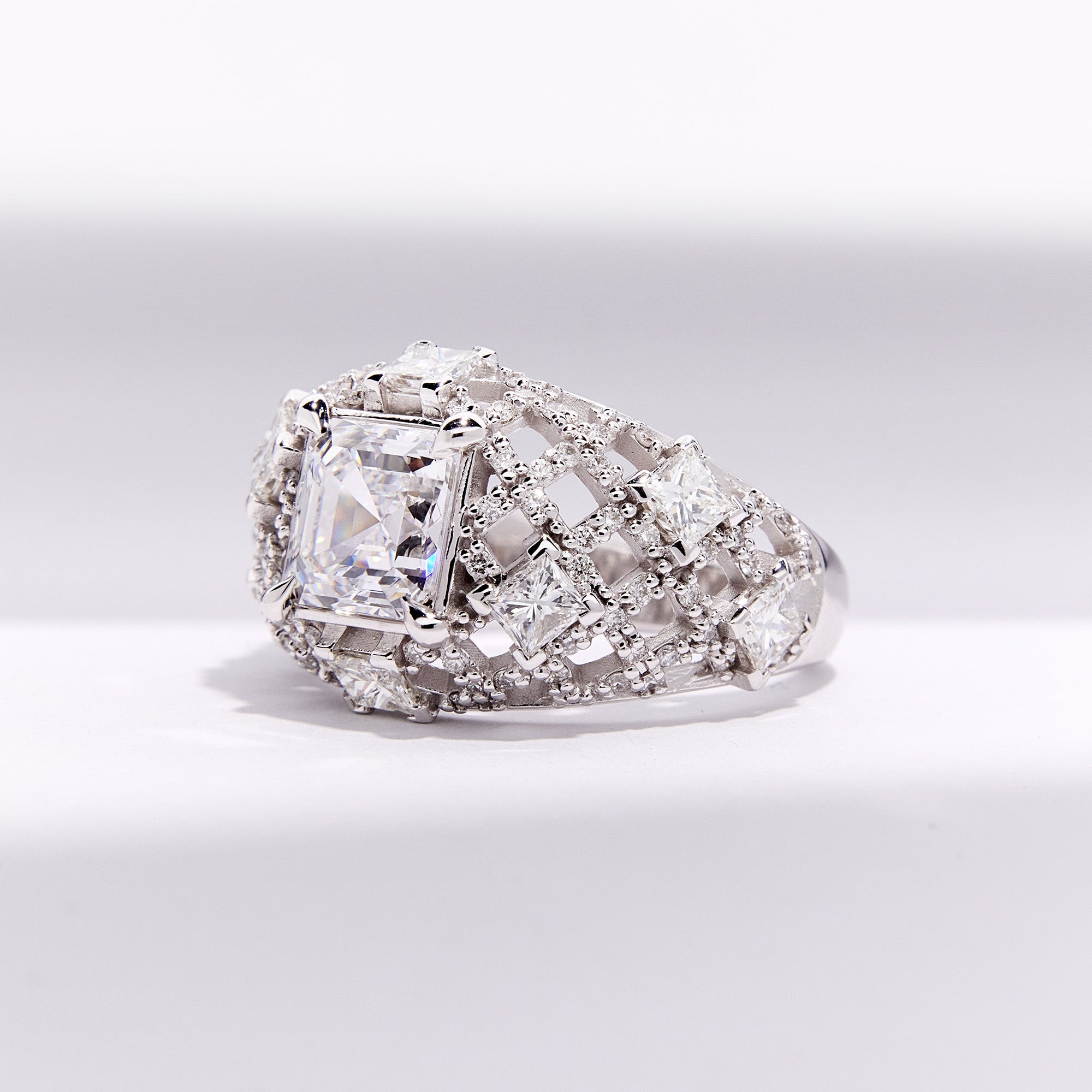 Pantheon Ring in white gold with emerald-cut diamond and architectural lattice of brilliant diamonds, shown in side view.