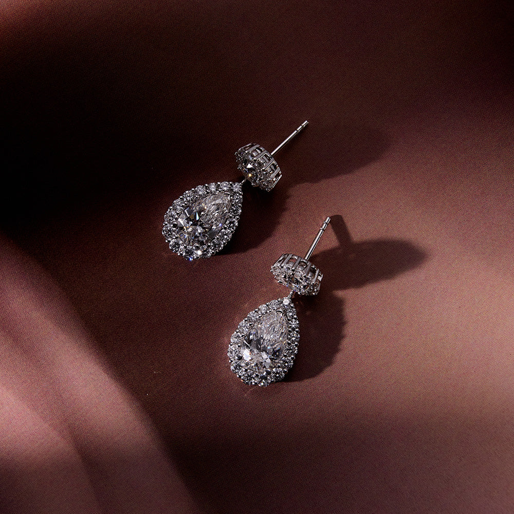 Elegant earrings featuring pear-shaped diamond drops and round brilliant diamond studs with halos