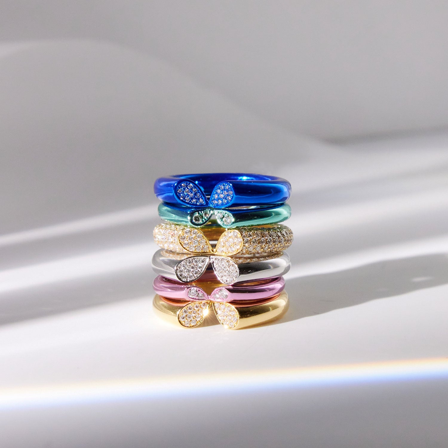 Whispers of Love rings in different sizes, colour and metal finish, stacked on top of each other.