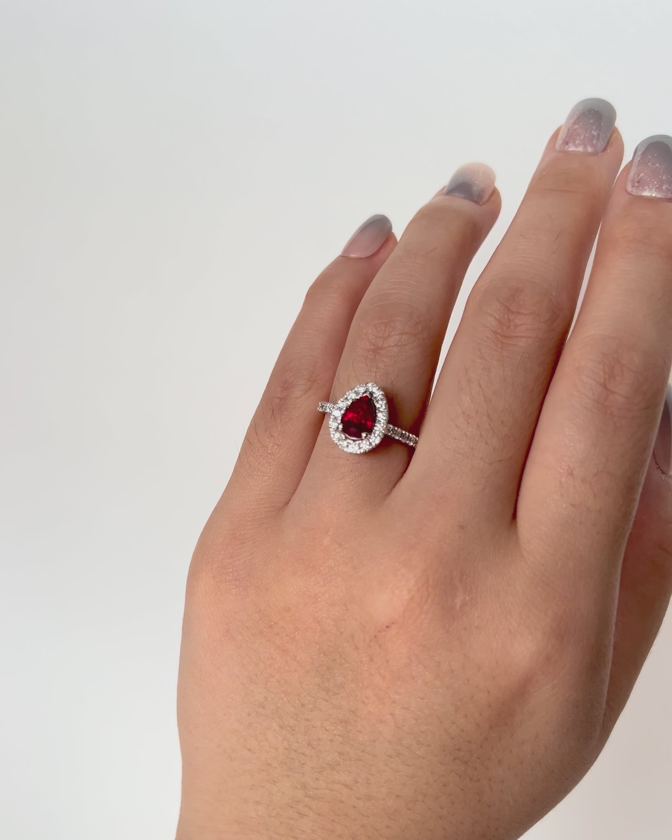 Pear-shaped ruby ring with diamond halo and shoulder accents in 18k white gold