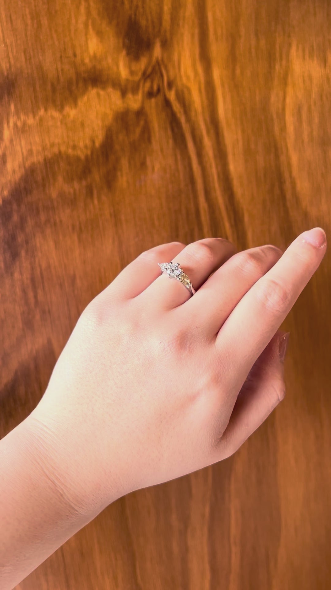 18k white gold Trilogy Engagement Ring featuring radiant round centre diamond and pear-cut pink & yellow side stones, timeless and modern, worn on hand model.