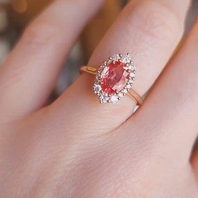 Unique Oval Padparadscha sapphire ring with round diamond halo, 18k rose gold setting.